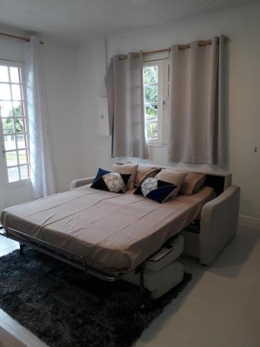 ein großes Bett in einem Zimmer mit Fenstern in der Unterkunft Gite les Bananiers in Saint-Joseph