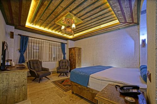 a bedroom with a bed and a desk and chairs at Termessos Hotel in Goreme