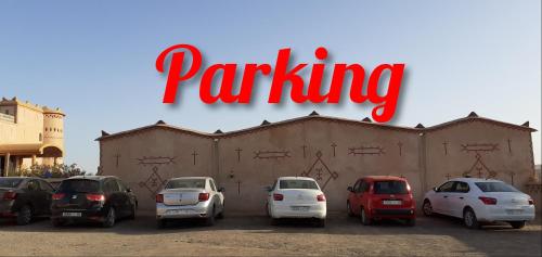 a parking lot with cars parked in front of a building at Overnight Desert Camp in Merzouga