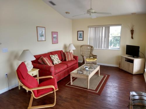 a living room with a red couch and chairs at Seahorse Landing #503 Gulf Front Vacation Condo in Cedar Key