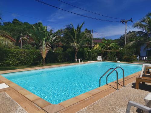 a swimming pool with blue water and palm trees at Weixiao Lanta Resort in Ko Lanta