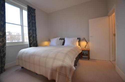 ein Schlafzimmer mit einem Bett und einem großen Fenster in der Unterkunft Notting Hill Sleeps 5 in London