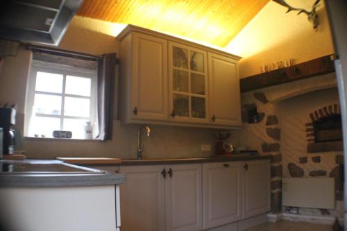 een keuken met witte kasten, een raam en een oven bij Vakantiehuis Le Vieux Tilleul in Pionsat
