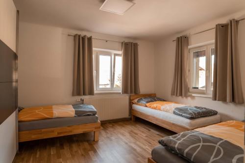 a bedroom with two beds and two windows at Moderne Ferienwohnung mit Ausblick in Bad Goisern