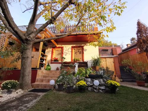 a house with a tree and flowers in the yard at Kisház Apartman in Eger