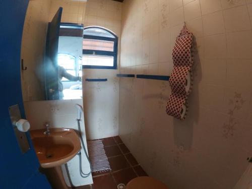 a bathroom with a sink and a toilet and a mirror at Suítes Pé na Areia in Barra do Sahy