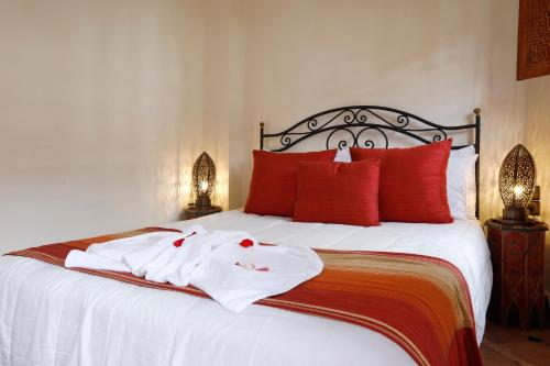 a bed with white sheets and red pillows at Riad Daria Suites & Spa in Marrakech