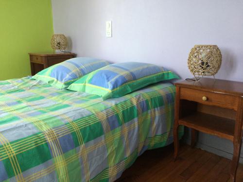 a bedroom with a bed with a green and blue comforter at Petite maison proche de Montbéliard in Sainte-Suzanne