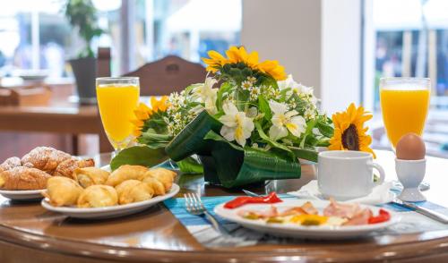 a table with breakfast foods and flowers and orange juice at Paralia Beach Boutique Hotel in Paralia Katerinis