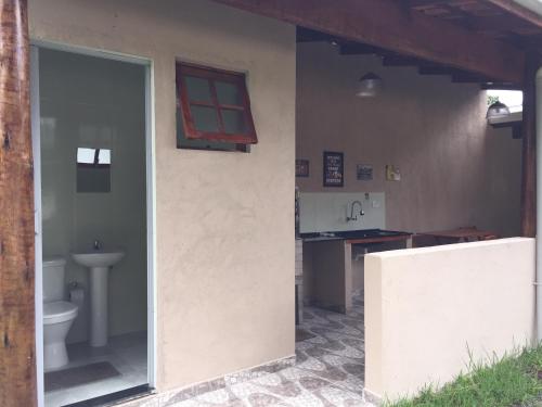 a bathroom with a toilet and a sink and a window at Casa em frente à praia Boracéia in Boracéia