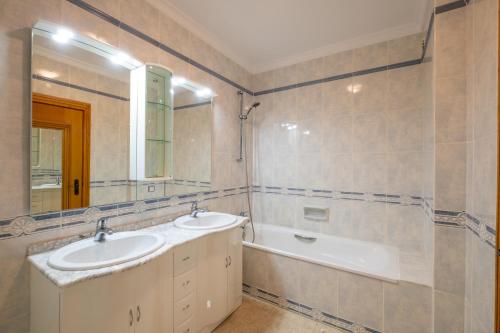 uma casa de banho com 2 lavatórios, uma banheira e um espelho. em VR Galé Mar em Albufeira