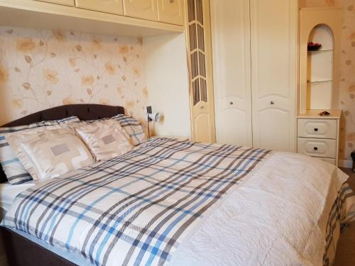 Schlafzimmer mit einem Bett mit einer blauen und weißen Bettdecke in der Unterkunft Spacious Bungalow in Romford with parking in Romford