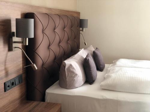 a bedroom with a bed with a headboard and two pillows at Intergroup Business & Design Hotel Ingolstadt in Kösching