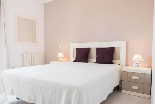 a white bedroom with a large white bed with purple pillows at Casa Bella Vista in Moraira