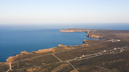 an aerial view of the ocean and a mountain at Aldeia Caiçara Surf House in Sagres