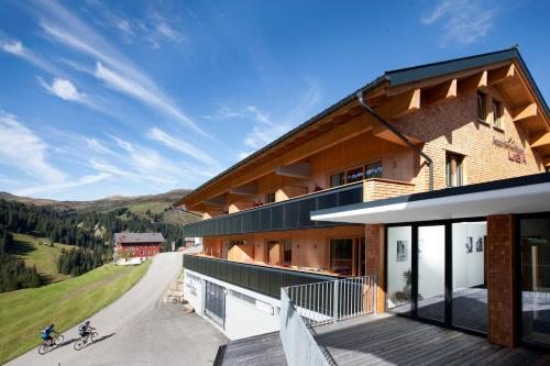 ein Haus in den Bergen mit zwei Personen auf Fahrrädern in der Unterkunft Appartementhaus Uga in Damüls