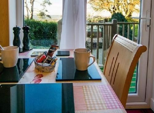 mesa de comedor con vistas a un balcón en Cosy Snug with shower ensuite - It has beautiful countryside views - Only 3 miles from Lyme Regis, Charmouth and River Cottage - It has a private balcony and a real open fireplace - Comes with free private parking, en Axminster