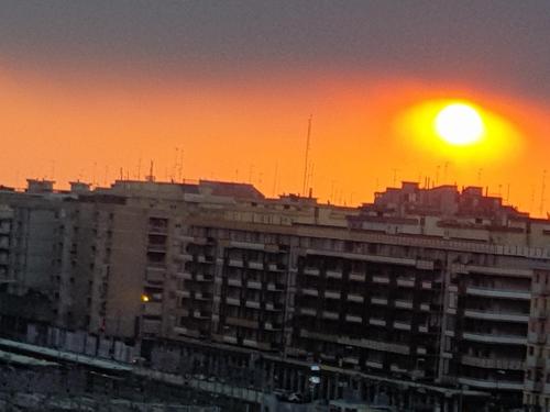 a sunset over a building with the sun in the sky at B&B GANAJ - Corso Italia 89 - BARI in Bari