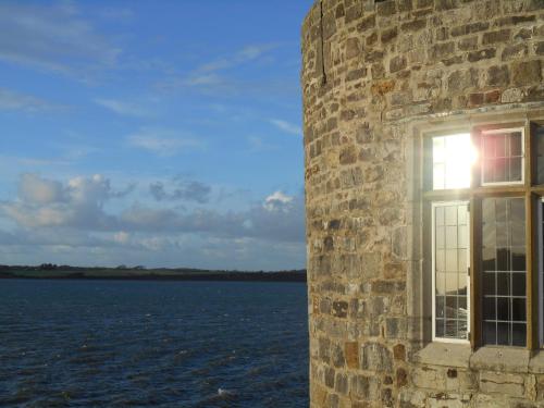 a window of a stone building looking out at the water at Victoria House Room Only Accommodation in Caernarfon