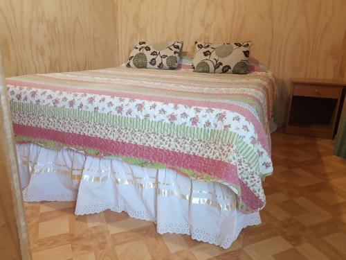 a bed with a pink and white blanket and pillows at Departamento Hikari in Puerto Natales