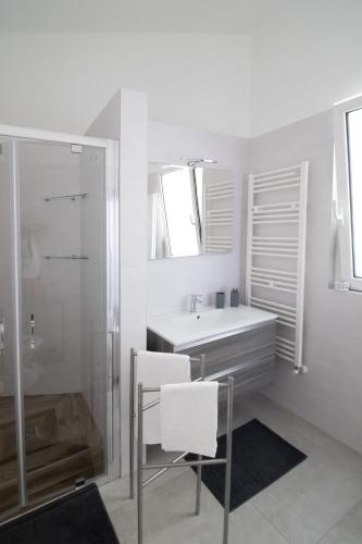 a white bathroom with a sink and a shower at Tra Sole e Mare in Monopoli