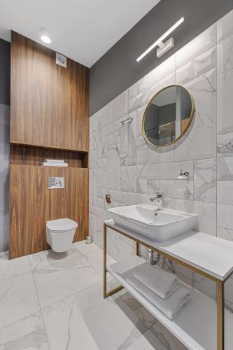 a bathroom with a sink and a toilet and a mirror at Aparthotel Krzywa Kamienica in Łódź