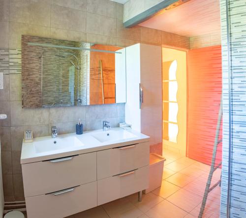 La salle de bains est pourvue d'un lavabo blanc et d'un miroir. dans l'établissement Paisible Maison entière 140m2 avec véranda vue sur la campagne, à Renwez