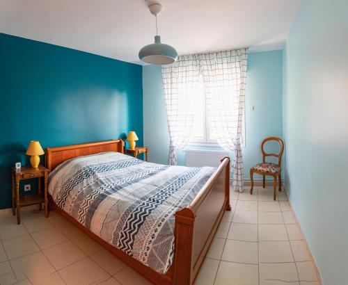 - une chambre avec un lit et un mur bleu dans l'établissement Paisible Maison entière 140m2 avec véranda vue sur la campagne, à Renwez