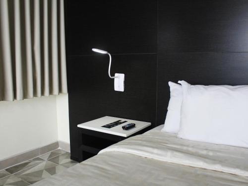 a bedroom with a bed and a nightstand with a lamp at Hotel Corona Plaza in Rosarito