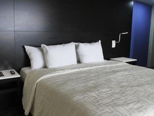 a bedroom with a large bed with white pillows at Hotel Corona Plaza in Rosarito