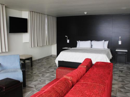 a hotel room with a bed and a red couch at Hotel Corona Plaza in Rosarito
