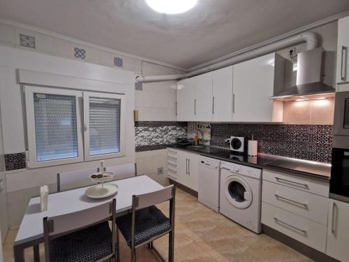 - une cuisine avec des placards blancs, une table et un évier dans l'établissement Casa Coqueta y confortable en Oviedo, à Oviedo