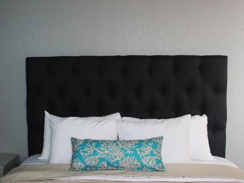 a bed with a black headboard and a pillow at Hotel Corona Plaza in Rosarito