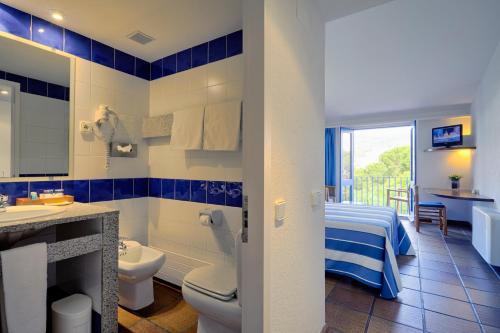 Hotel Blaumar Cadaqués في كاداكيس: حمام ازرق وابيض مع مغسلة ومرحاض
