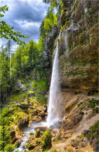 a waterfall on the side of a mountain at SavaDolinka House in Mojstrana