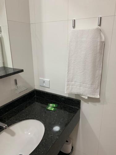 a bathroom with a sink and a mirror and a towel at Pousada Santa Fé in Aparecida