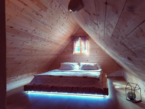 a bed in a wooden room with a window at Vodenica Vrelo Chalets in Vrelo Koreničko