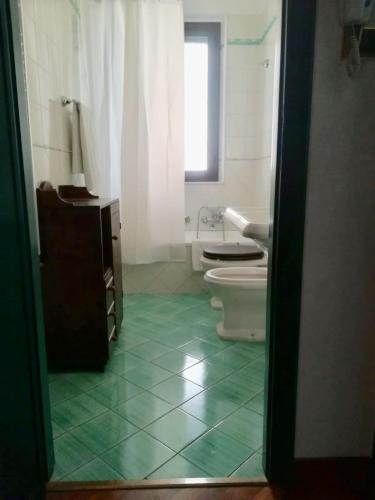 ein Bad mit WC und grünem Fliesenboden in der Unterkunft Smile House Castelbuono in Castelbuono