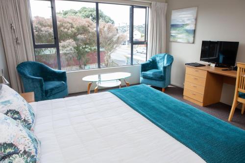 Habitación de hotel con 1 cama, 2 sillas y escritorio. en Airport Motor Lodge, en Wellington