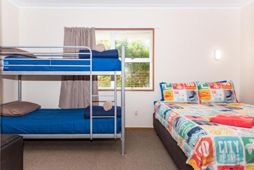 a bedroom with two bunk beds and a window at Te Ra Waitangi in Paihia