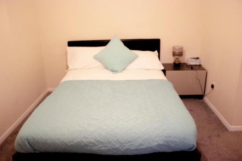 Una cama con una almohada azul encima. en Kempston Cosy Lodge, en Bedford
