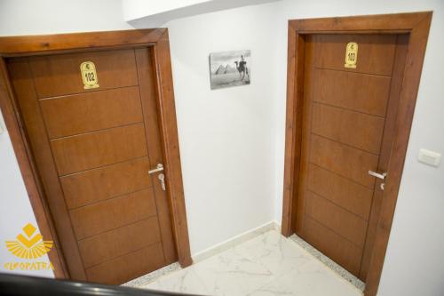two wooden doors in a room with white walls at Cleopatra Pyramids View Hotel in Cairo