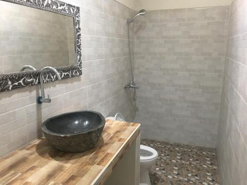 a bathroom with a black sink and a toilet at Arjuna Uluwatu Guest House in Uluwatu
