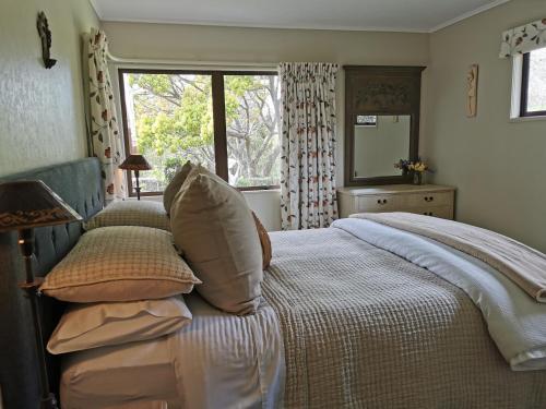 ein Schlafzimmer mit einem Bett mit Kissen und einem Fenster in der Unterkunft La Belle Vie Bed & Breakfast in Napier