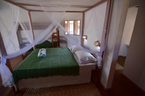 a bedroom with a bed with a teddy bear on it at Pousada Velho Bateau in Atins