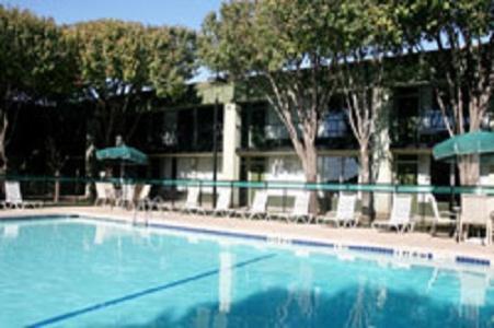a large blue swimming pool with chairs and umbrellas at Whitten Inn University in Abilene