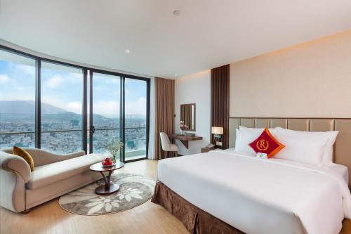 a hotel room with a bed and a couch and windows at Regalia Gold Hotel in Nha Trang