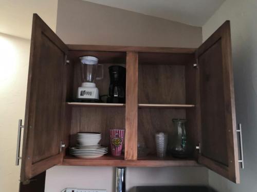 a wooden cabinet with dishes in it in a kitchen at KIA - PESQUERIA - AEROPUERTO MONTERREY a in Monterrey
