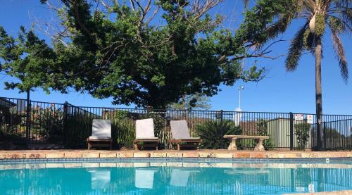 two chairs and a table next to a swimming pool at Hunter Oasis in Morpeth