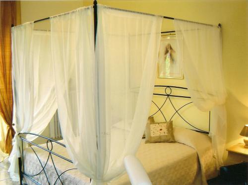 Monticello d'AlbaにあるCà 'd Peracaのベッドルーム(白いカーテン付きの天蓋付きベッド1台付)